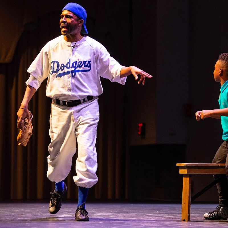 theatrical production with man portraying jackie robinson with little boy
